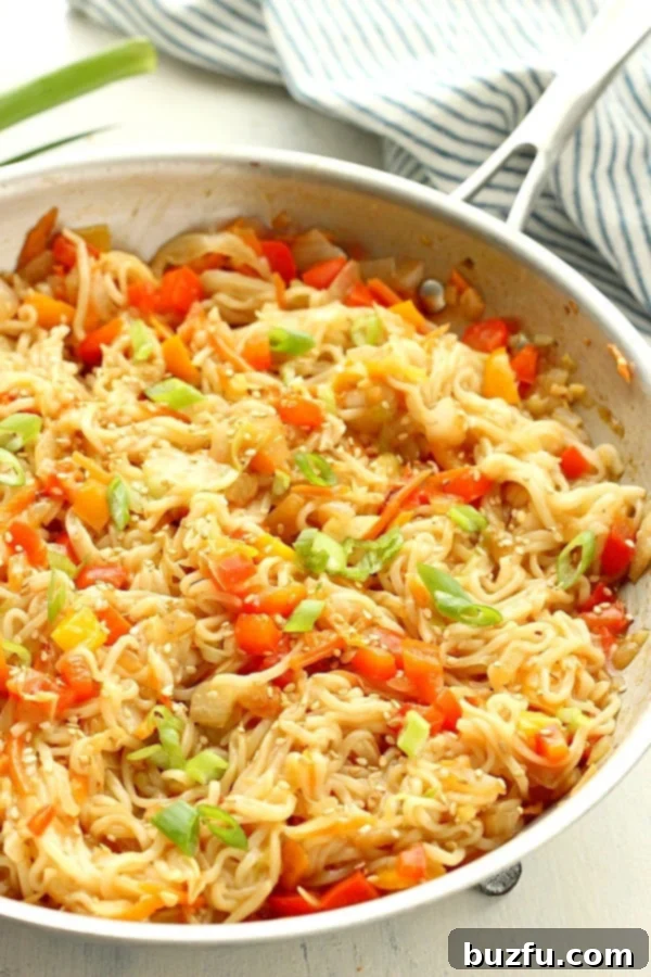 A serving of ramen stir fry in a bowl, garnished with sesame seeds and green onions.