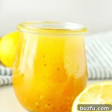 Bright Lemon Vinaigrette 5 Salad dressing in a jar next to lemons.