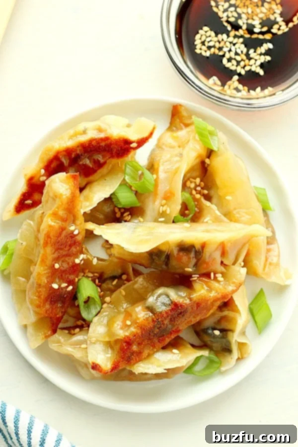 A close-up of beautifully pan-fried Asian dumplings, golden brown and crispy on the bottom, arranged enticingly on a white plate, showcasing their inviting texture.