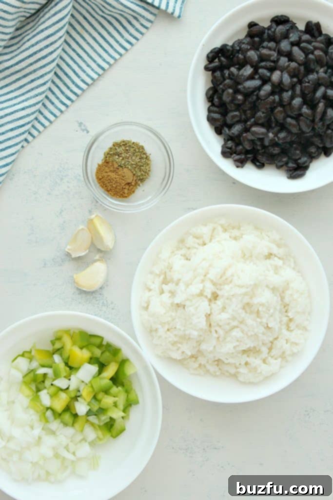 Fresh ingredients laid out: rice, black beans, bell peppers, onion, garlic, and spices on a white cutting board.