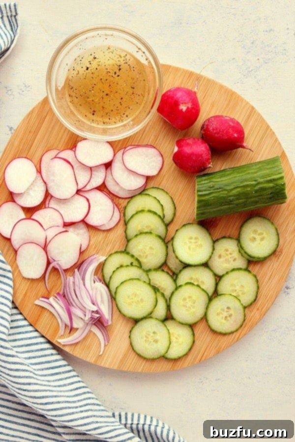 A vibrant selection of fresh ingredients for a quick radish salad, including whole radishes with green tops, a crisp English cucumber, a red onion, olive oil, and fresh herbs, artfully arranged on a rustic wooden cutting board.