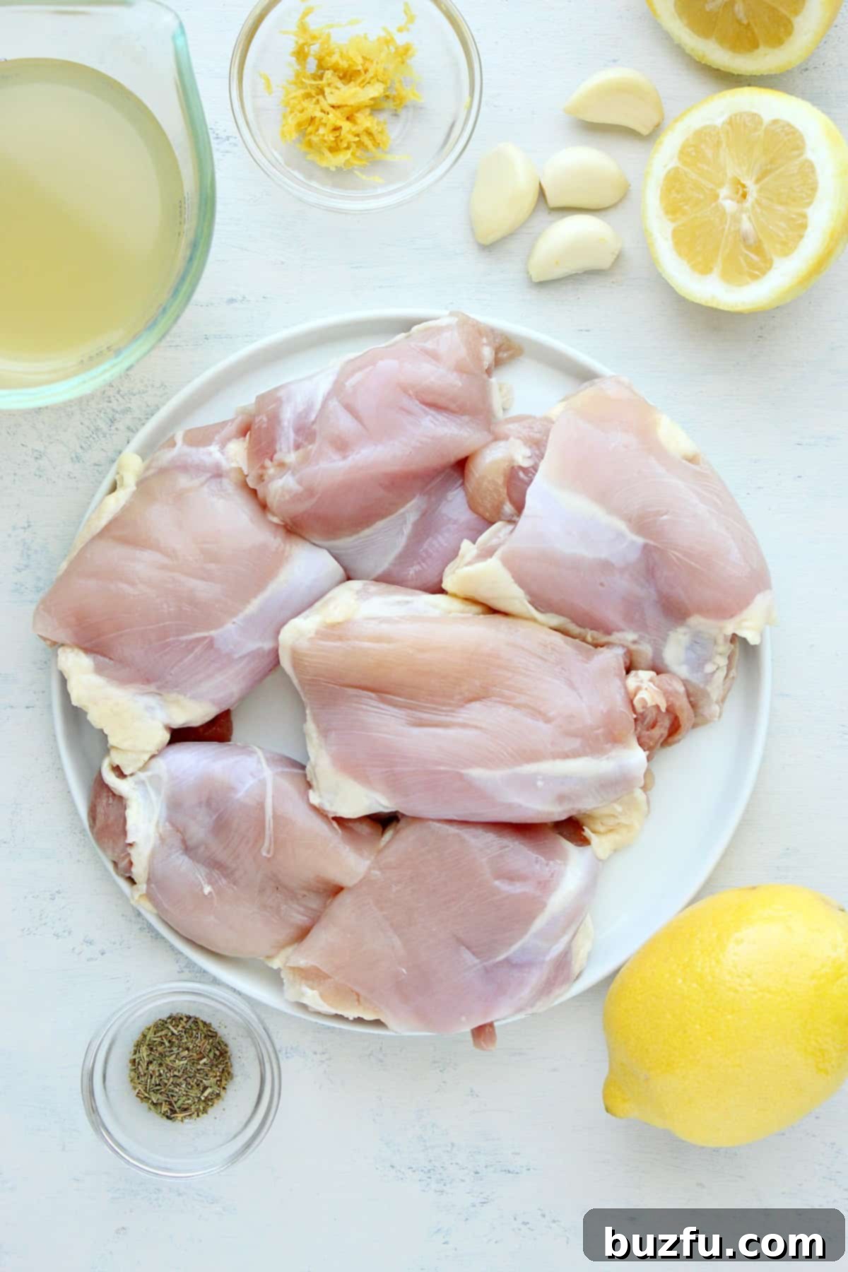 Chicken, seasoning and lemons on a white board.