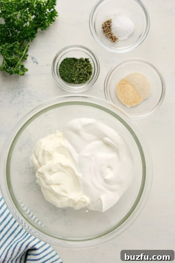 Collection of fresh ingredients for vegetable dip arranged on a white cutting board, including jars of mayonnaise and sour cream, and small bowls of dried dill, parsley, garlic powder, onion powder, salt, and pepper.