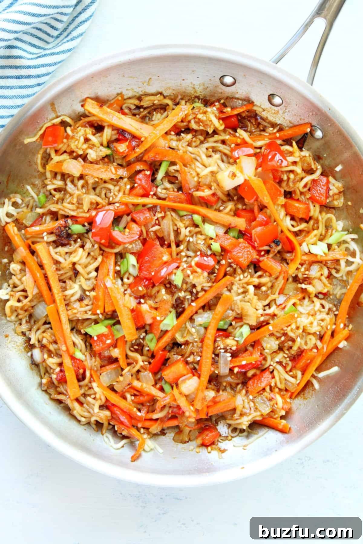 Crispy pan-fried noodles tossed with colorful stir-fried vegetables in a large skillet, ready to serve.