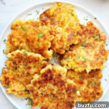 Irresistible Corn Fritters 3 Corn fritters on a white plate.