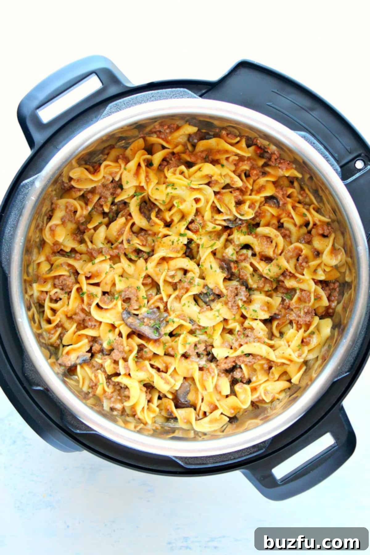 Bowl of creamy Instant Pot Beef Stroganoff with ground beef, egg noodles, and fresh herbs.