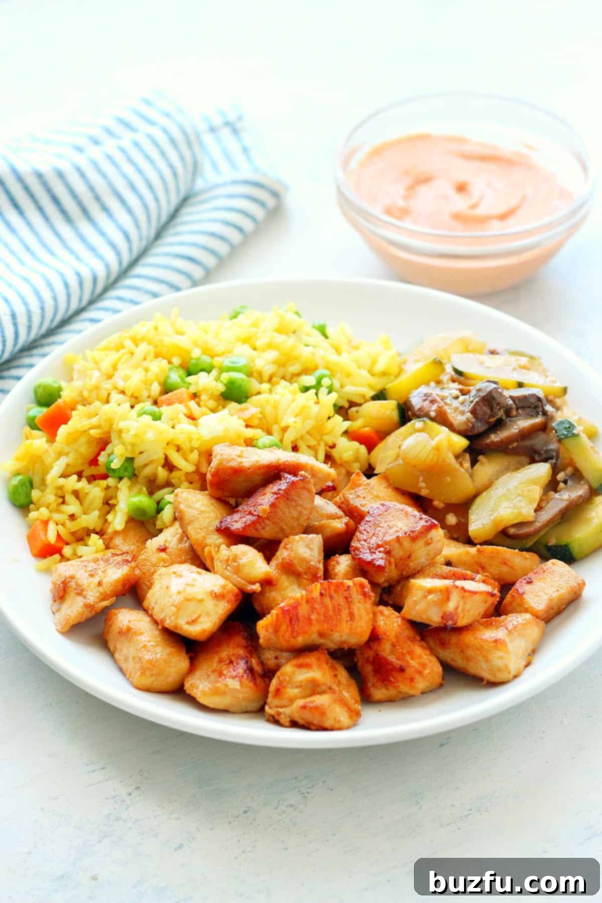 A perfectly portioned plate featuring hibachi chicken, fluffy white rice, and a vibrant mix of sautéed vegetables, garnished with fresh herbs.