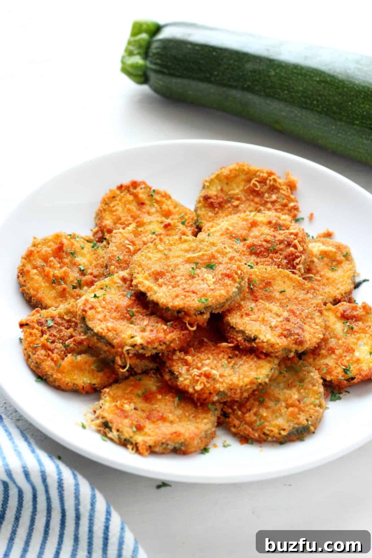 Golden brown Air Fried Zucchini crisps on a plate, ready to be served.