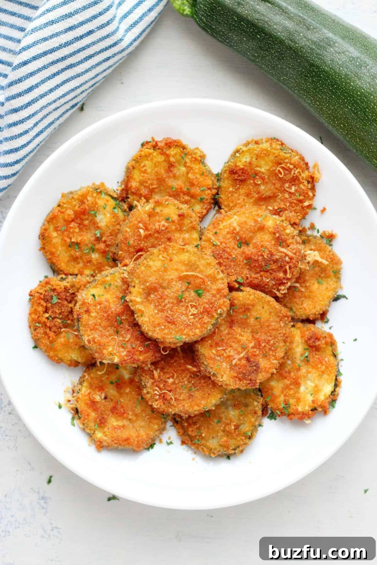 A plate of golden brown air-fried zucchini crisps, perfectly cooked and ready to eat.