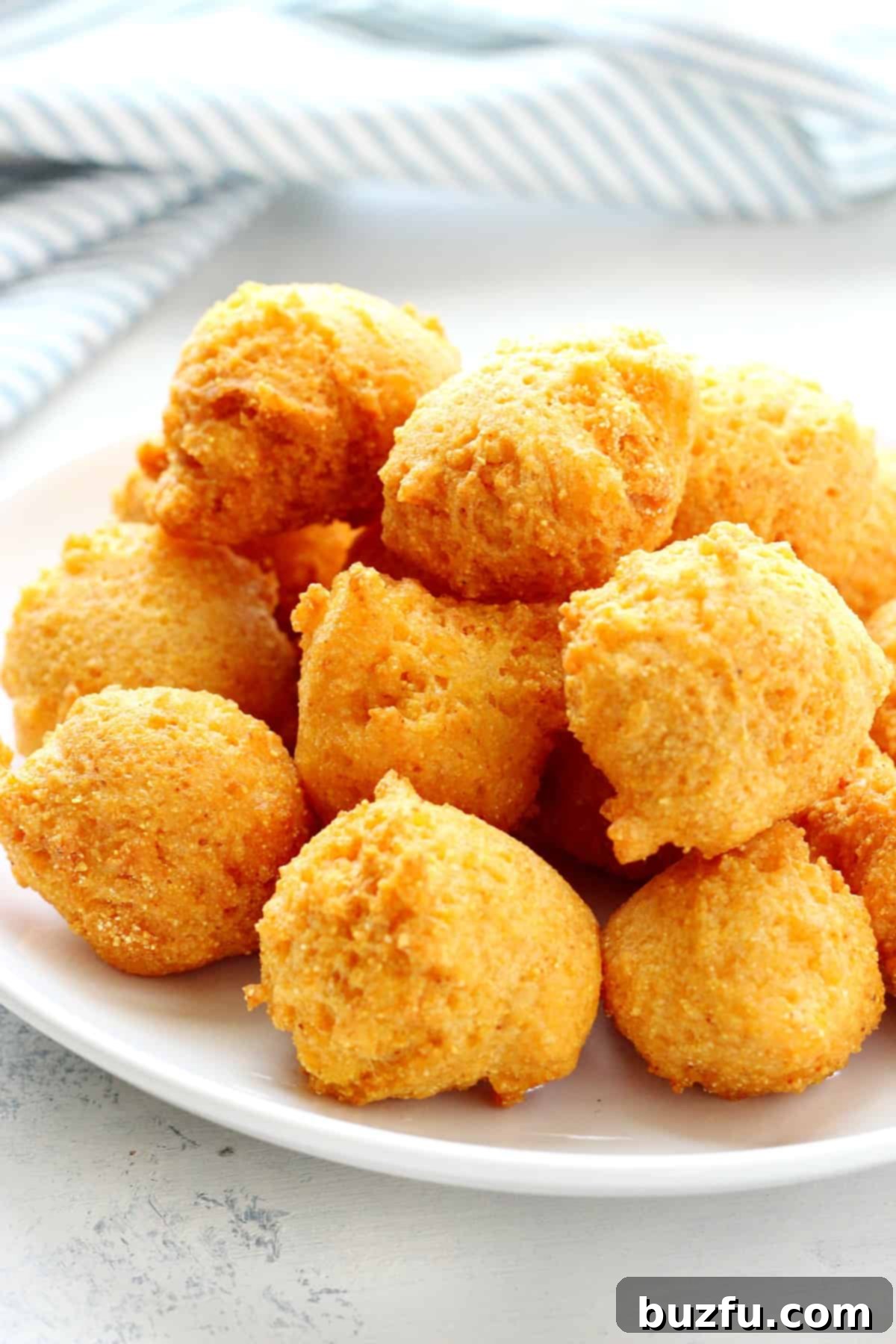 Fried hush puppies on a white plate, golden and crispy.