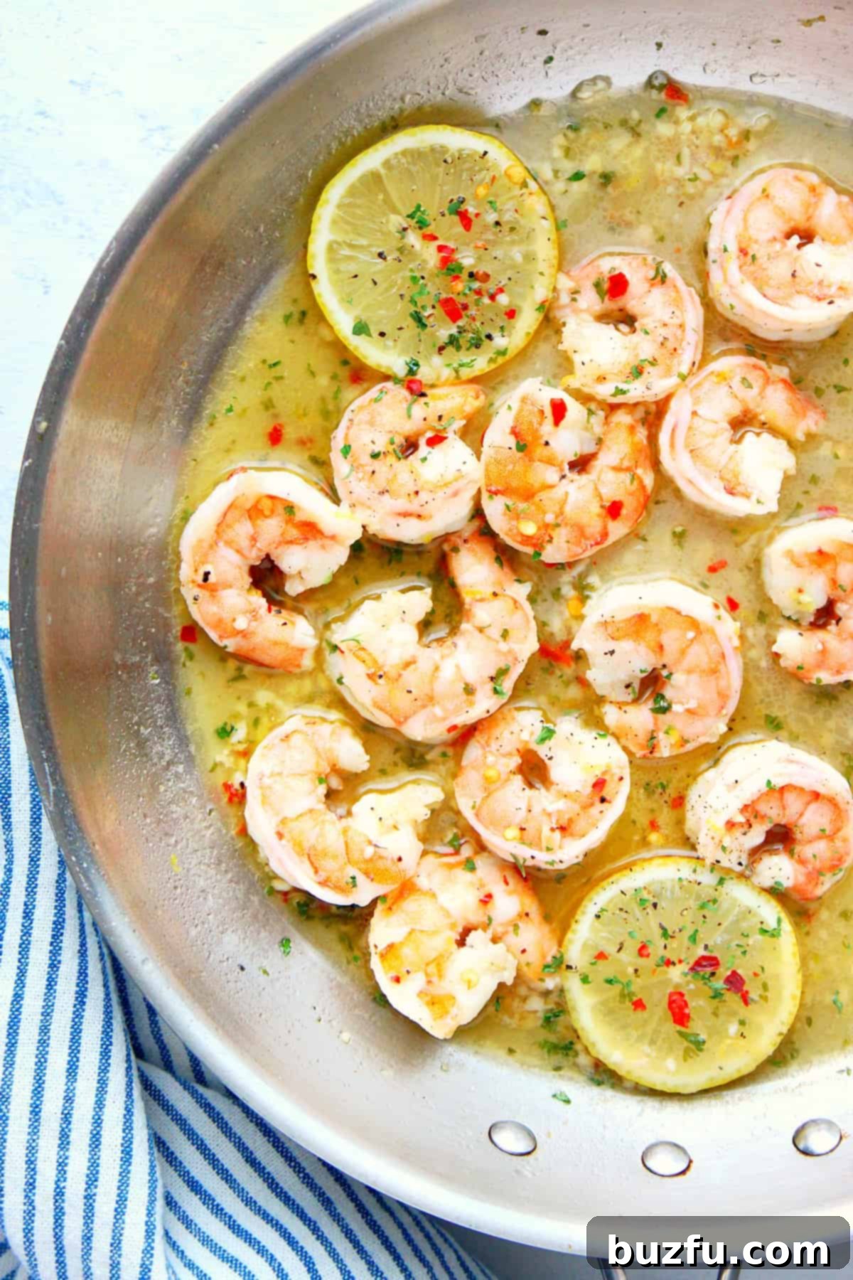 Shrimp and lemon in sauce in pan.