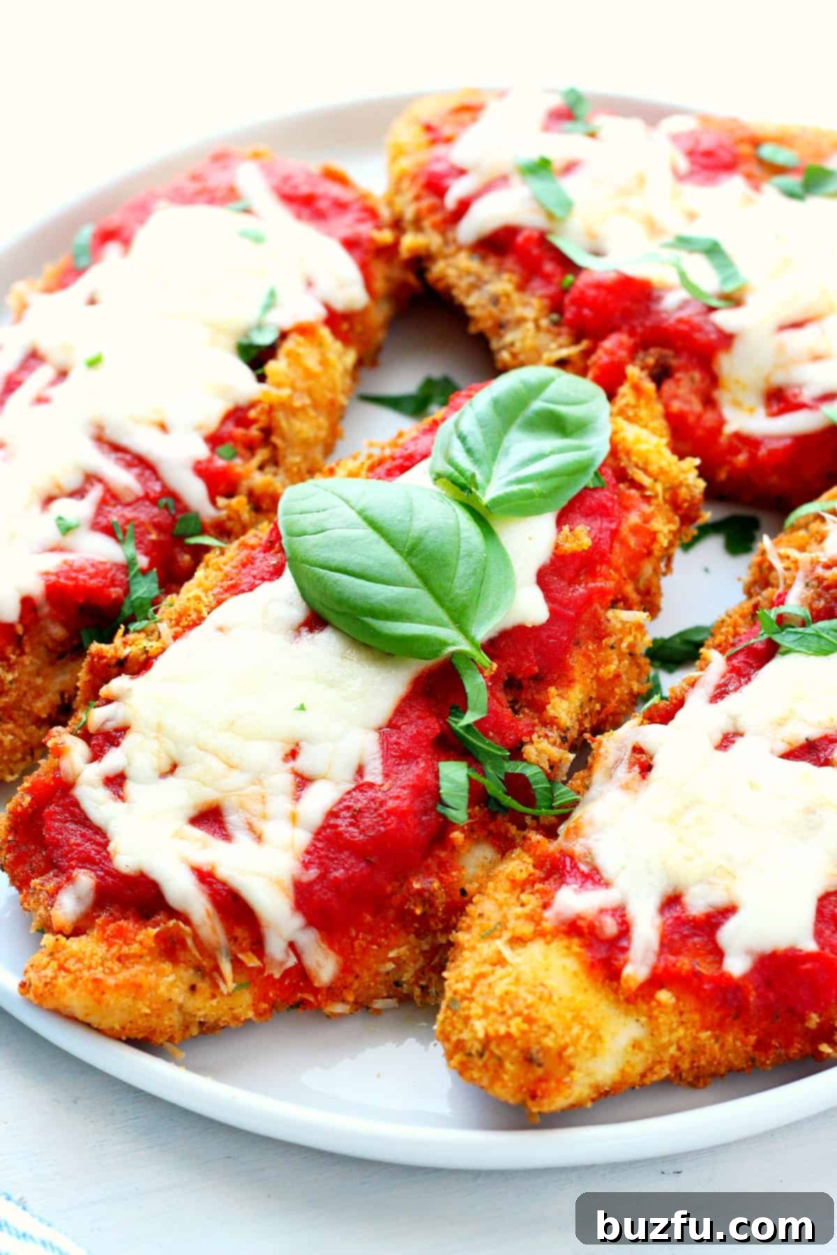 Crispy Air Fryer Chicken Parmesan, topped with melted mozzarella and rich tomato sauce, served on a plate with fresh basil garnish.