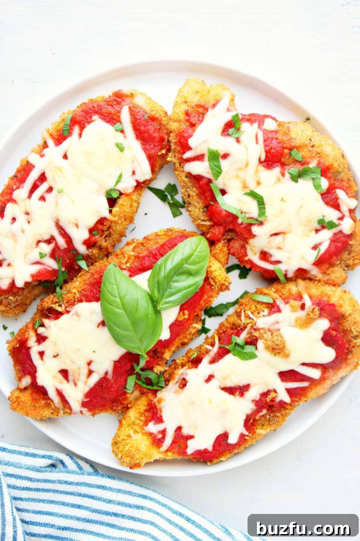 A perfectly cooked Air Fryer Chicken Parmesan cutlet, garnished with fresh herbs, resting on a white plate ready to be served.