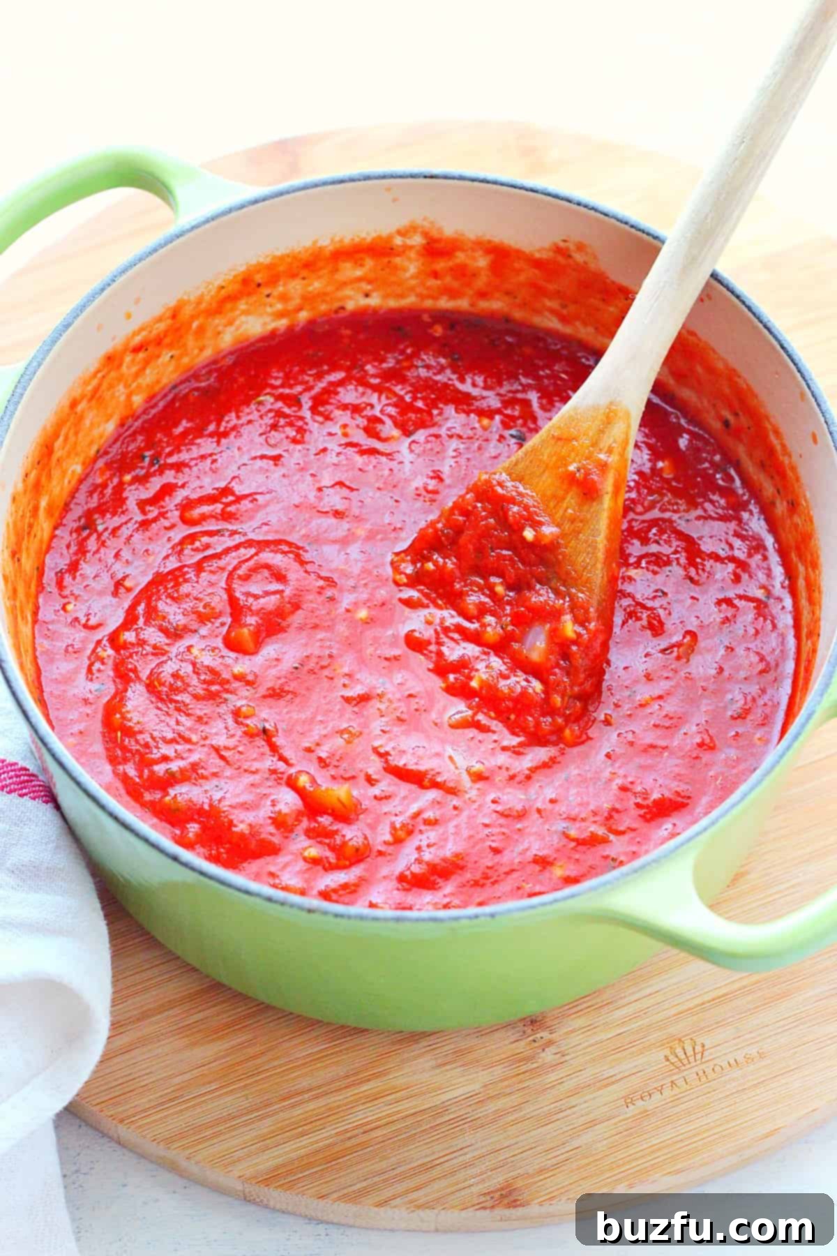 Tomato sauce in a green pot on a board.