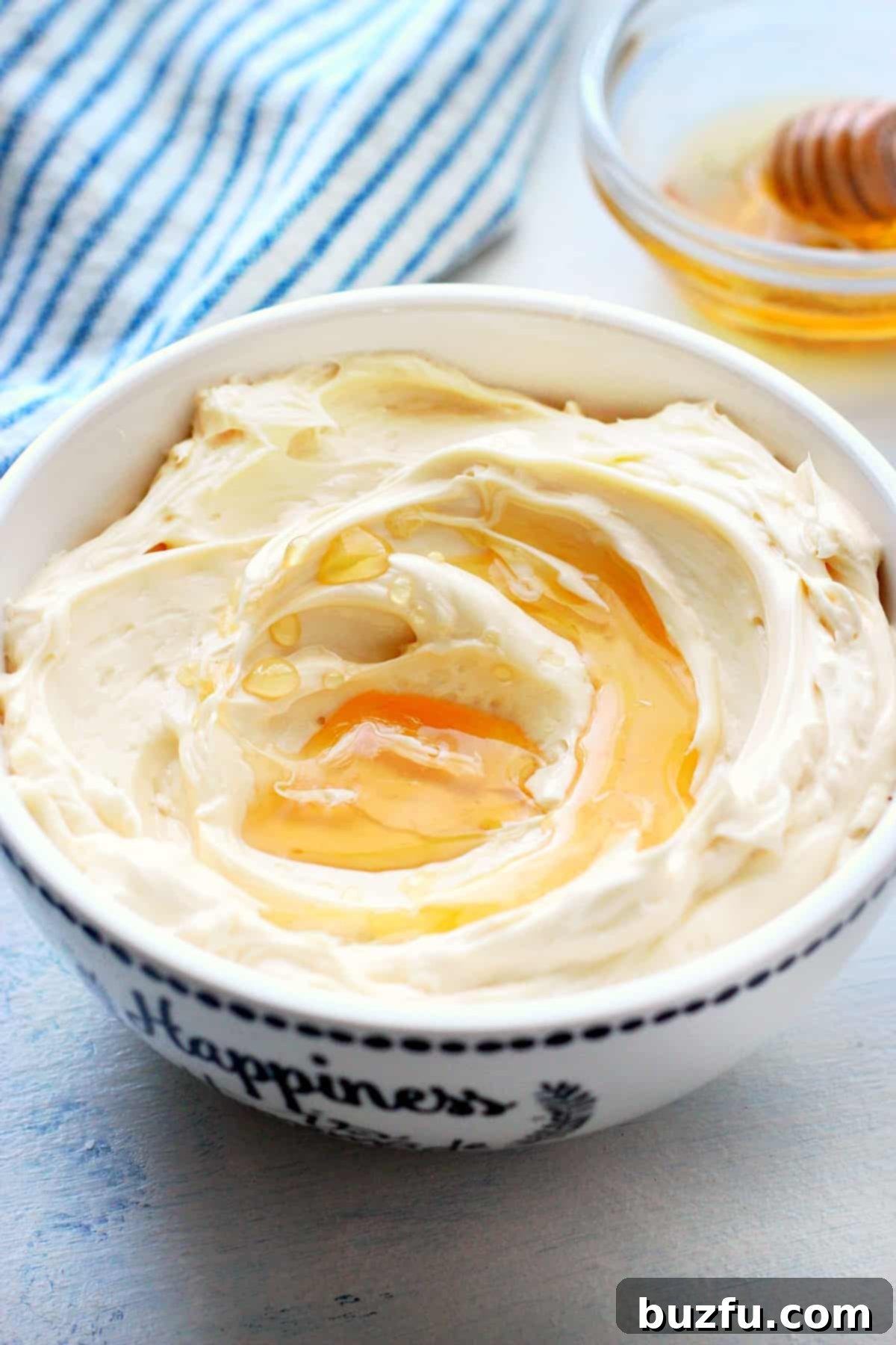 A creamy bowl of homemade honey butter, ready to be served, sitting on a wooden surface.