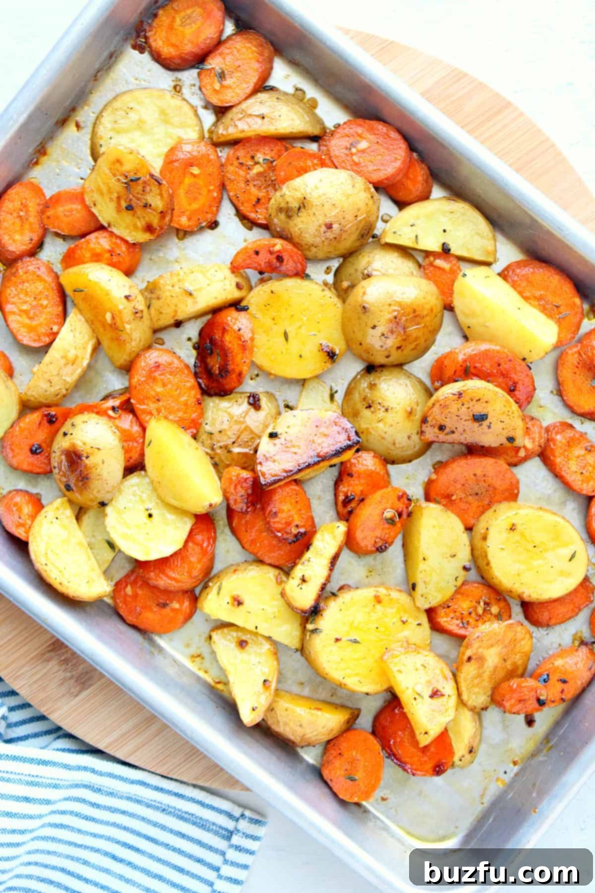 Golden Roasted Potatoes and Carrots Fresh from Oven Close-up of perfectly roasted potato and carrot chunks, slightly browned and tender, on a baking sheet fresh out of the oven.