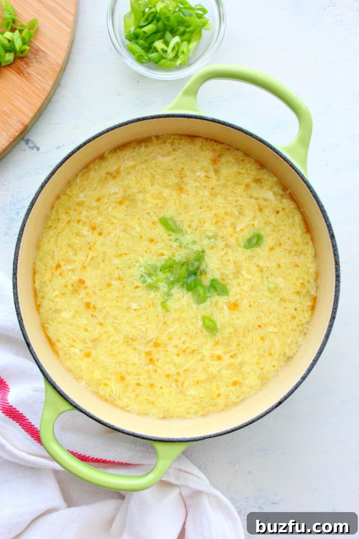 Easy Homemade Egg Drop Soup Recipe A steaming bowl of homemade Egg Drop Soup in a rustic Dutch oven, garnished with fresh green onions.