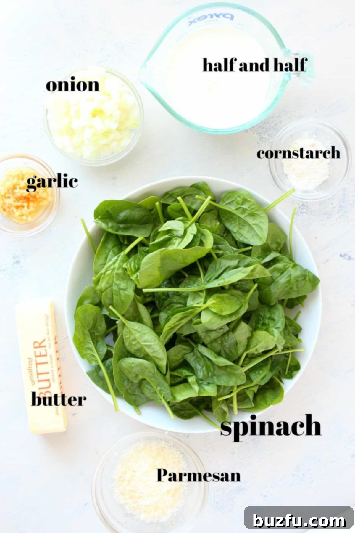 Fresh ingredients for creamy spinach on a cutting board.