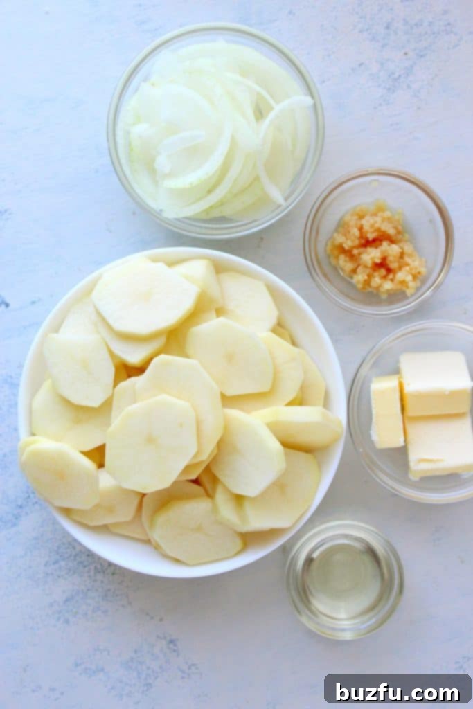 Caramelized Onion Potatoes 2 Fresh ingredients for Lyonnaise Potatoes laid out on a white cutting board, including Russet potatoes, yellow onion, garlic, and butter.