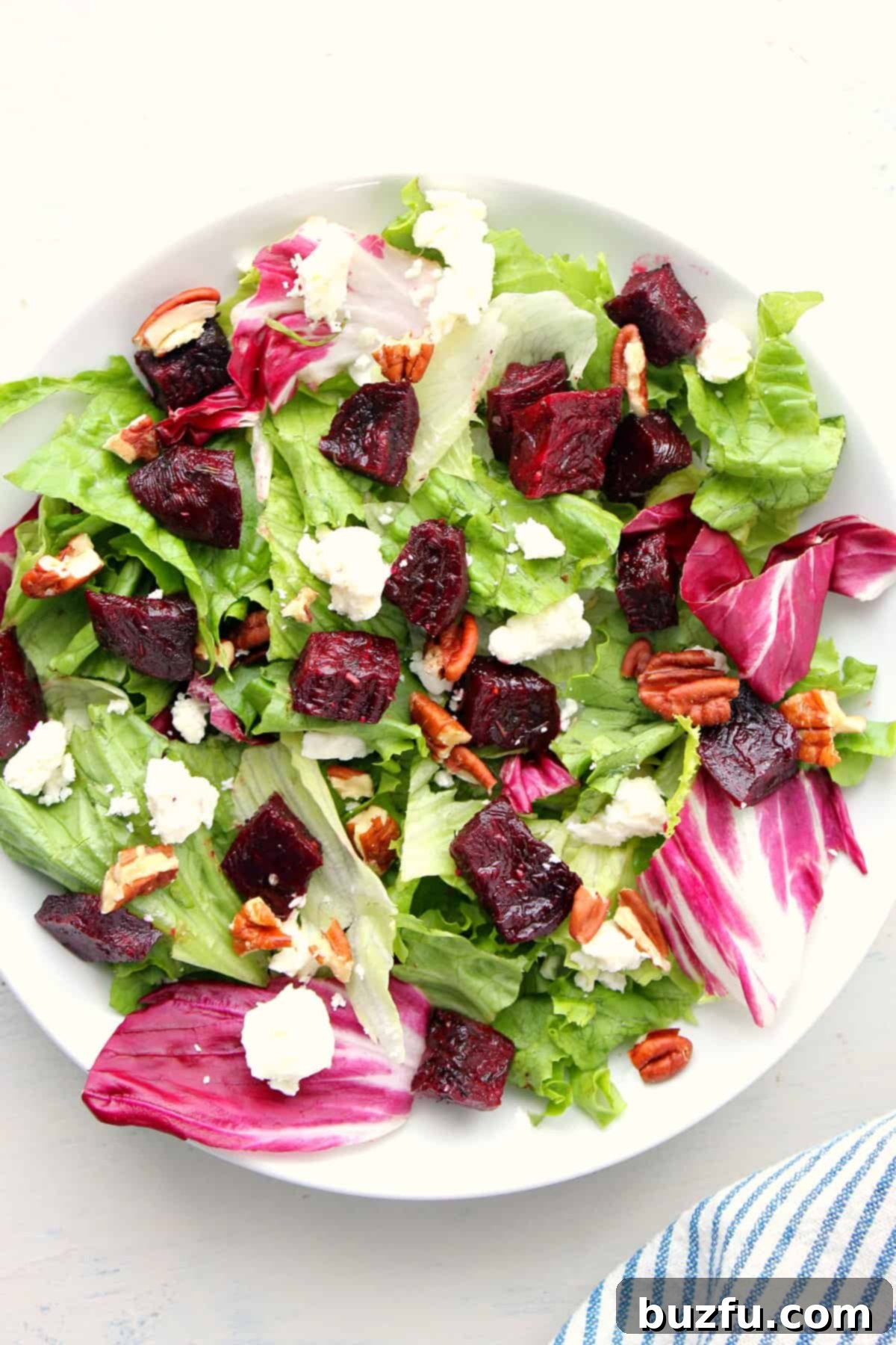 Roasted Beet Salad recipe A beautifully plated salad featuring vibrant roasted beets, fresh mixed greens, crumbled feta cheese, and toasted pecans, ready to be drizzled with dressing.