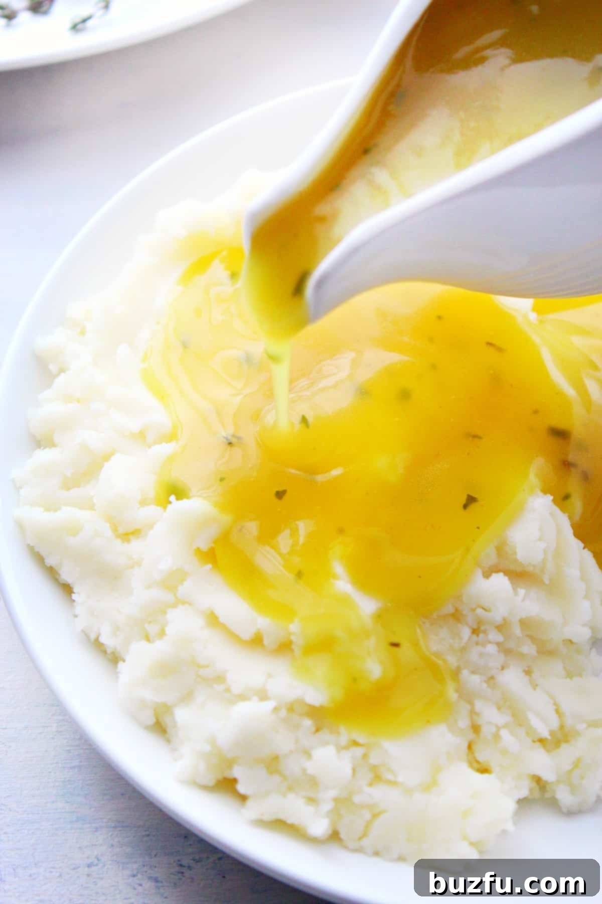 Rich, homemade turkey gravy generously poured over a serving of fluffy mashed potatoes, highlighting its perfect consistency and inviting color.