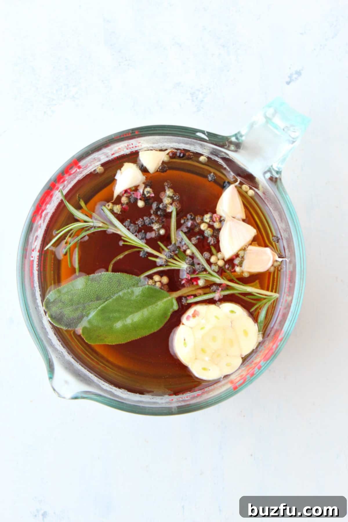 How to make turkey brine step-by-step All brine ingredients in a clear glass bowl, showcasing the vibrant colors and fresh herbs.