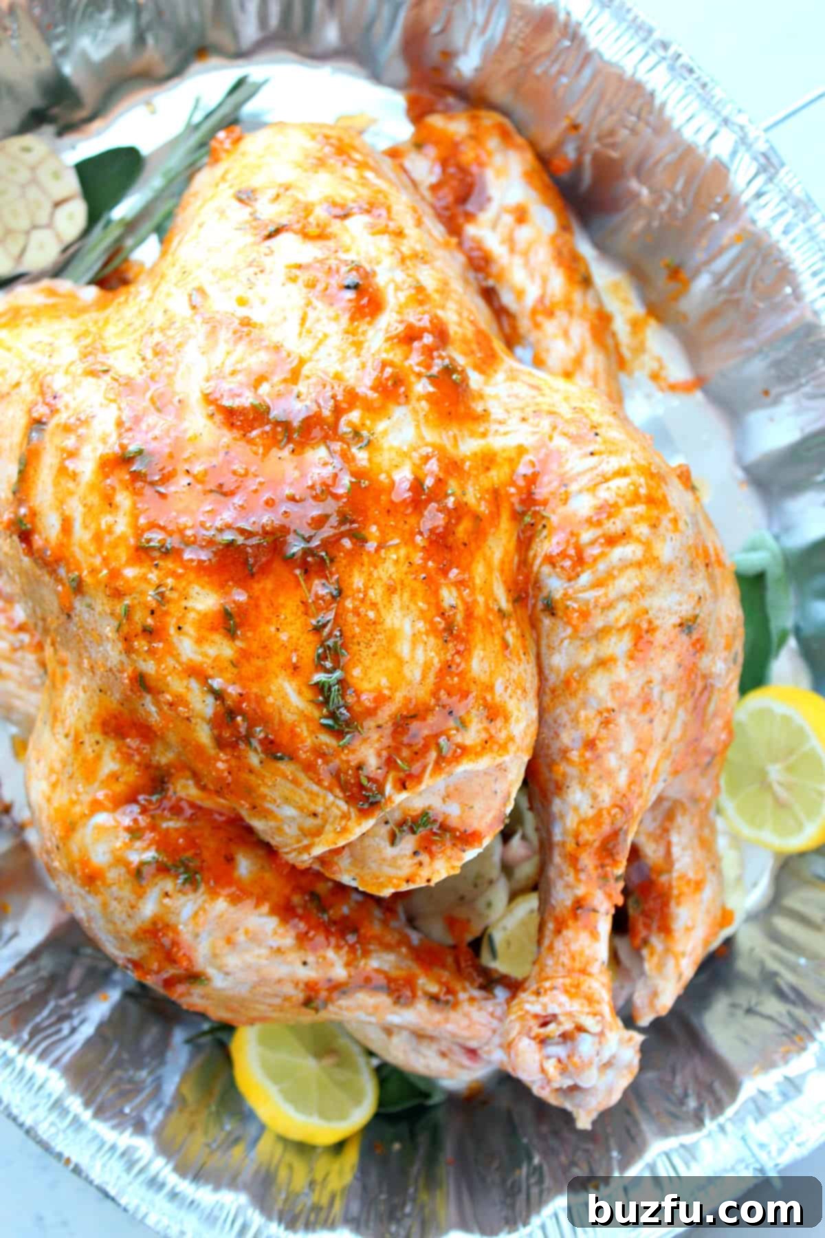 Raw turkey in a roasting pan, prepared and seasoned, ready to be placed in the oven.