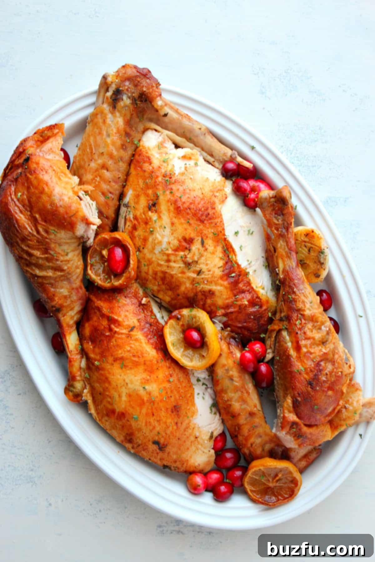 How to carve a turkey for Thanksgiving. A perfectly roasted Thanksgiving turkey, golden brown and glistening, resting on a large serving platter with fresh herbs as garnish.