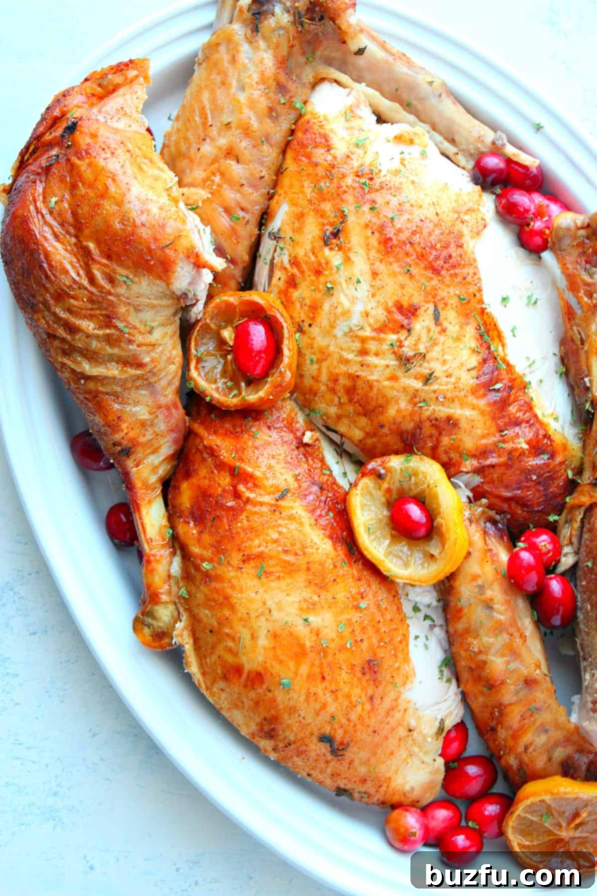 How to carve Thanksgiving turkey for a perfect presentation. A beautifully arranged platter of carved turkey, showcasing neatly sliced breast meat, drumsticks, and thighs, garnished with fresh rosemary and cranberries, ready for serving at a festive holiday meal.