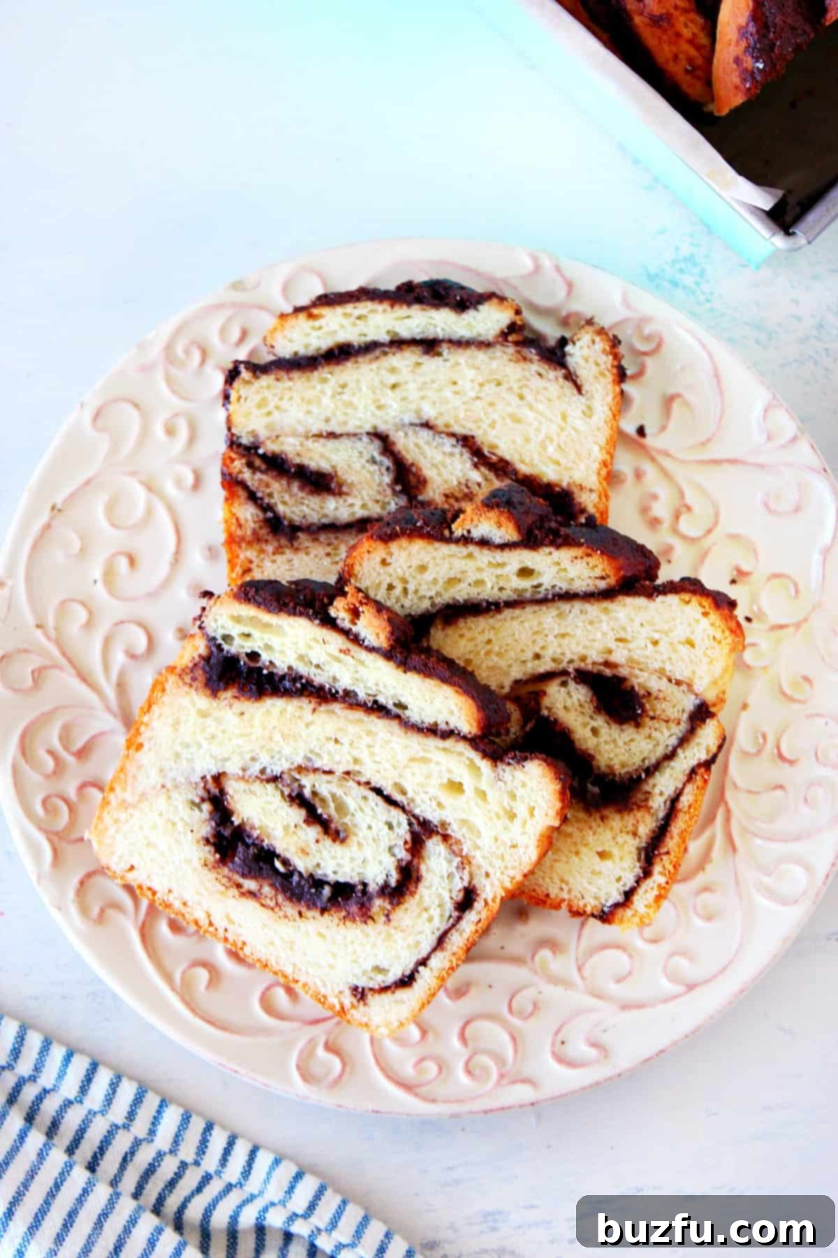 Thick slices of chocolate babka, revealing its intricate layers of dough and rich chocolate filling, arranged elegantly on a white plate.