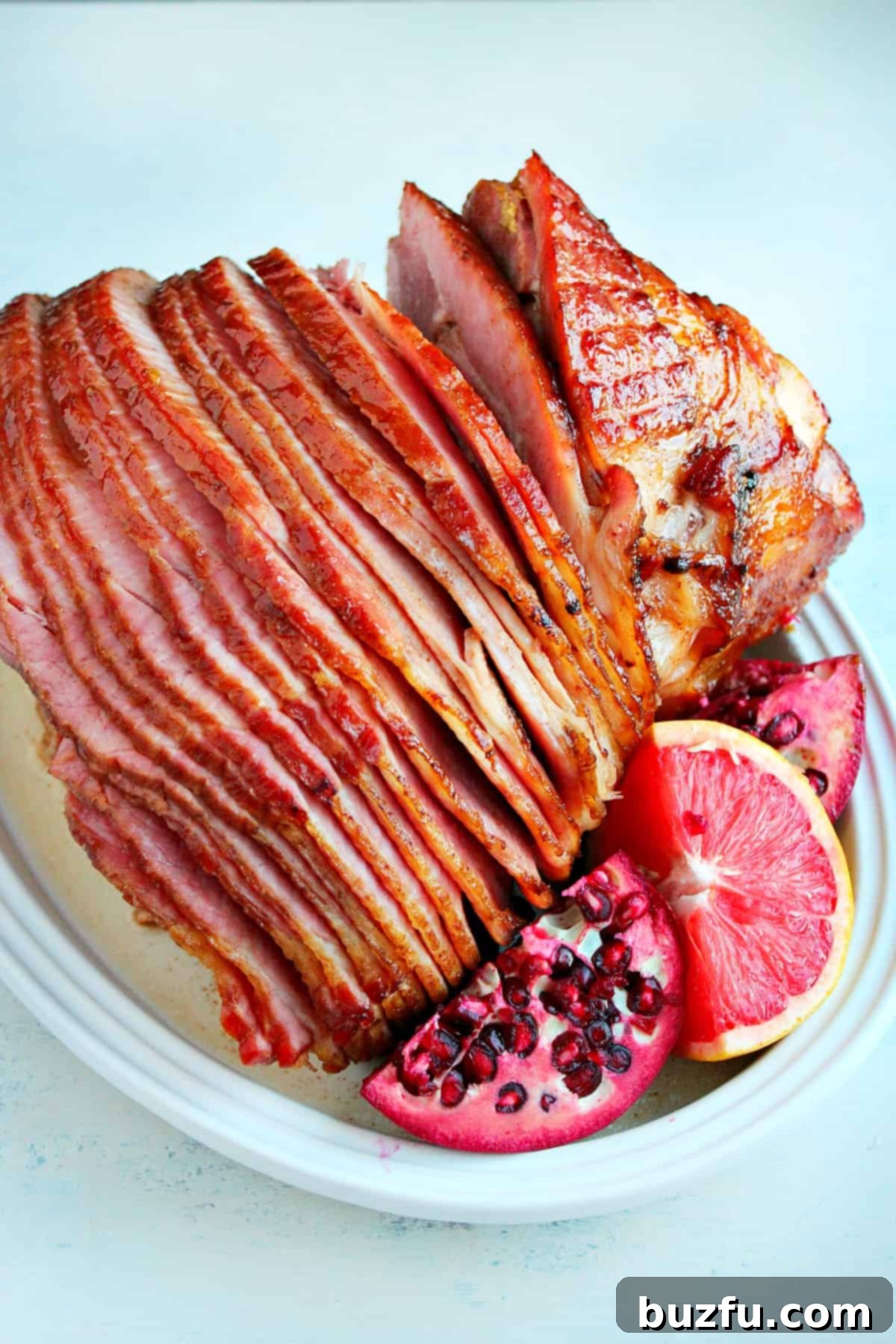 How to make baked Christmas ham: Spiral cut ham A beautifully presented spiral-cut ham on a white plate, showcasing its easy-to-carve slices and golden glaze, perfect for a holiday meal.