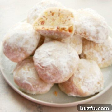 Sweetest Snowfall Cookies 3 Classic Snowball Cookies on a plate, dusted with powdered sugar.