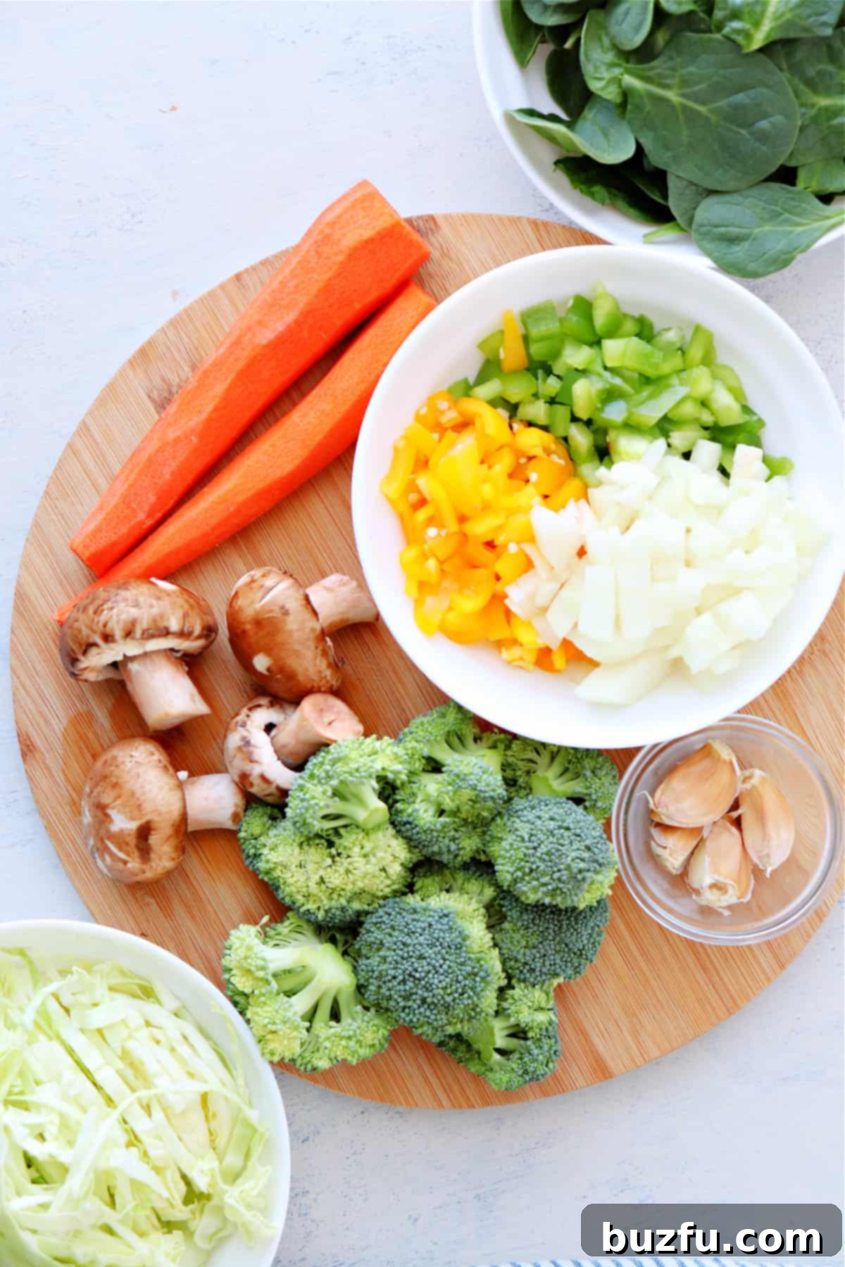 Freshly chopped assortment of vegetables, including onions, bell peppers, broccoli florets, and carrots, ready for the stir fry.