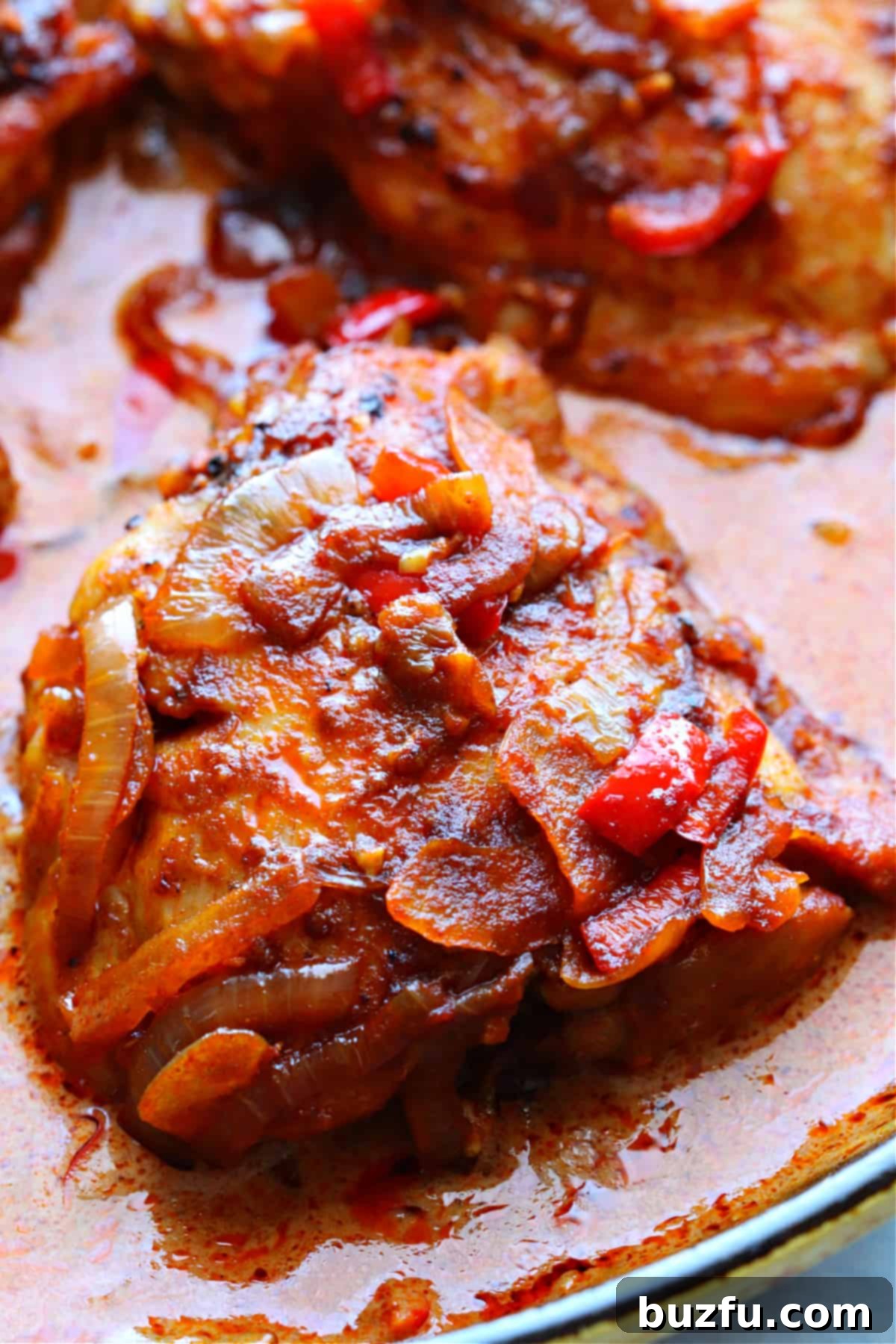 Close-up of a tender chicken thigh in a generous pool of rich, creamy chicken paprikash sauce, garnished with fresh parsley.