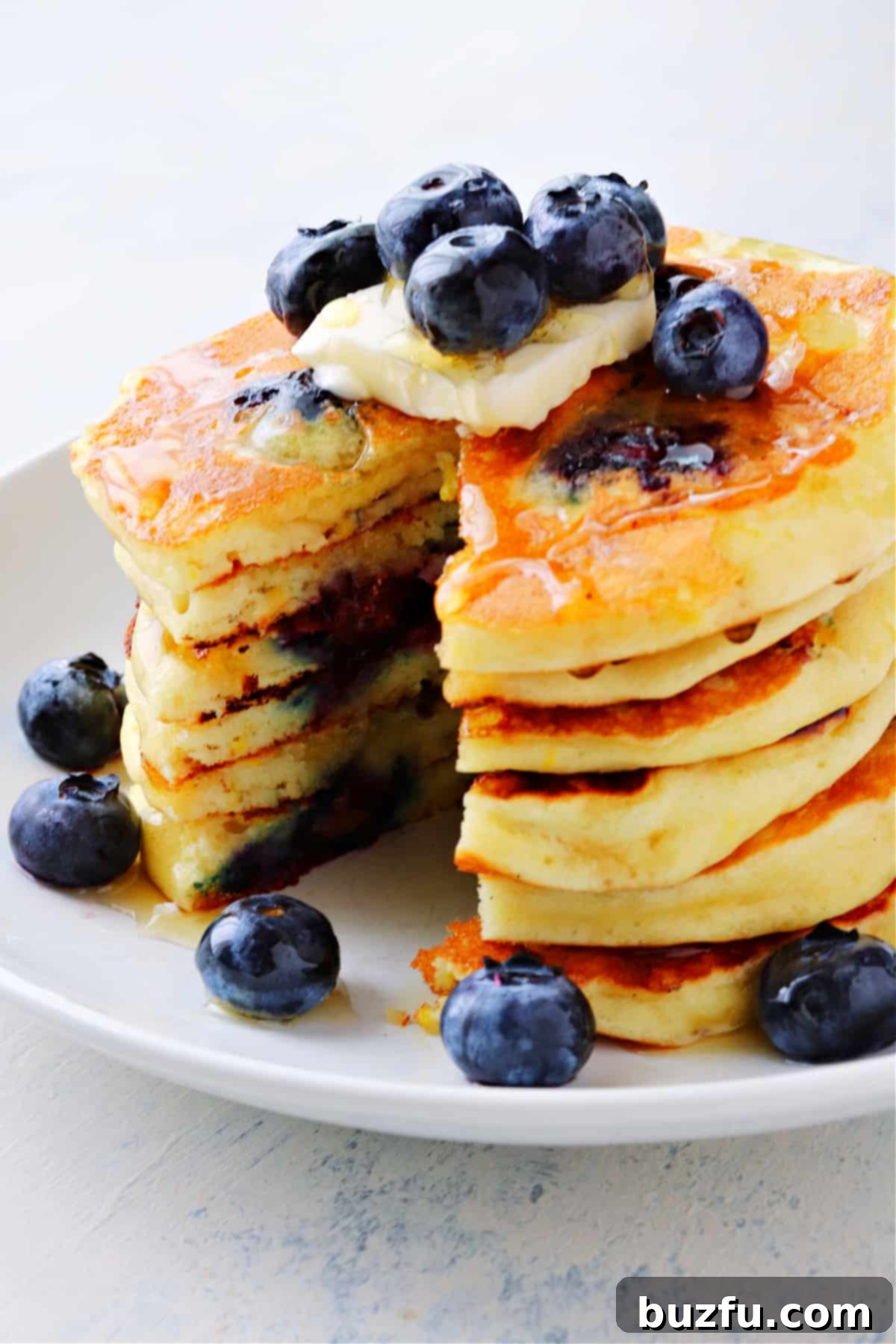 Best Blueberry Pancakes recipe Stack of golden-brown blueberry pancakes topped with fresh blueberries and a generous drizzle of honey.