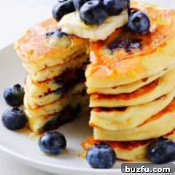 Fluffy Blueberry Bliss Pancakes 3 Stack of golden-brown blueberry pancakes topped with fresh blueberries and a generous drizzle of honey.