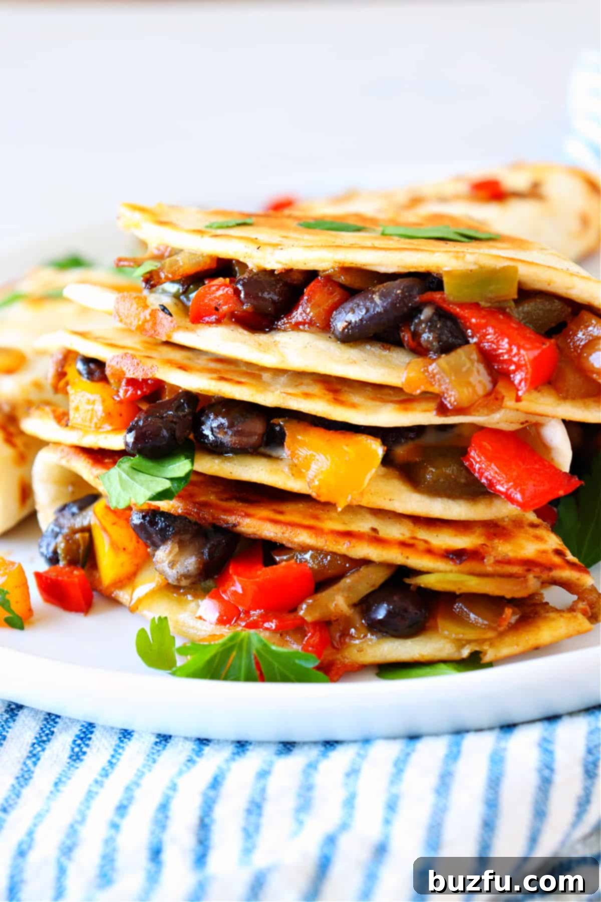 Delicious Vegetable Quesadillas Recipe Stacked quesadillas with colorful vegetables on a white plate, garnished with fresh cilantro.