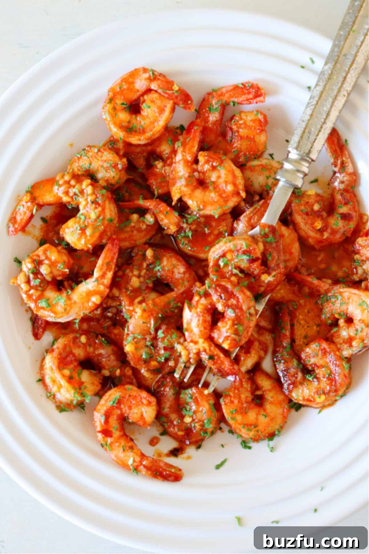 A beautifully plated dish of vibrant Cajun shrimp, garnished with fresh herbs, ready to be served.