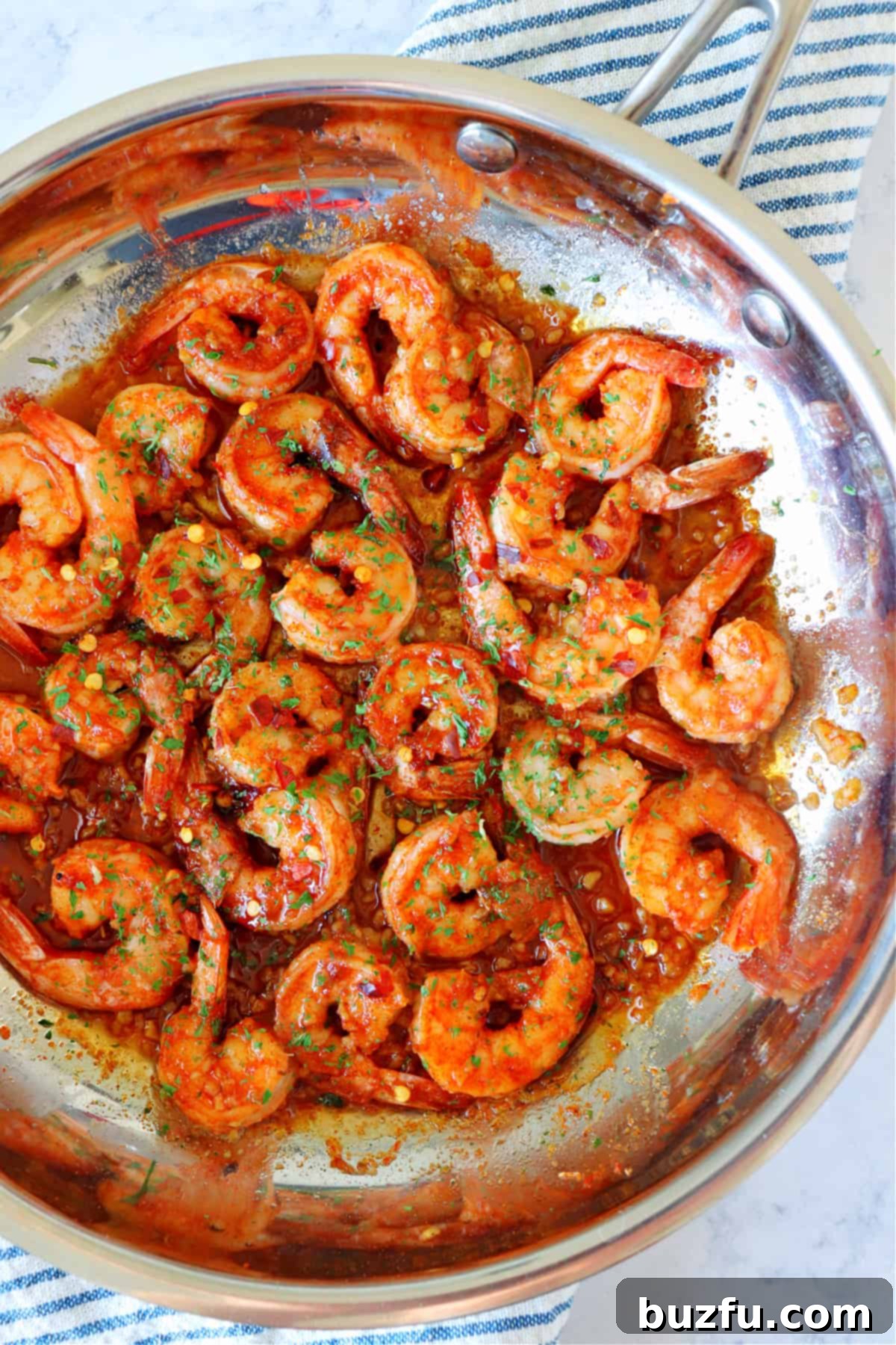 A close-up shot of seasoned raw shrimp waiting in a pan before cooking, highlighting the texture and spice blend.