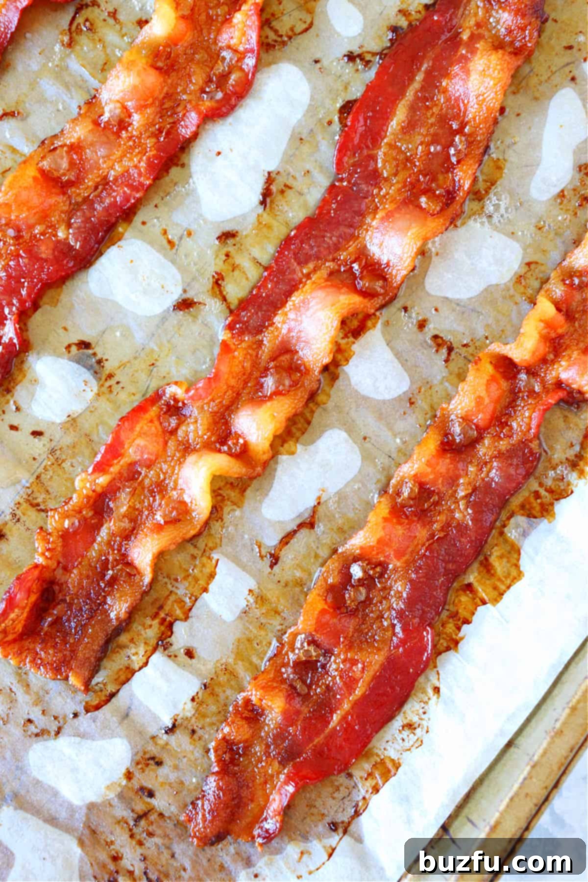 How to Cook Bacon in the Oven Crispy bacon sizzling on parchment paper, fresh out of the oven.