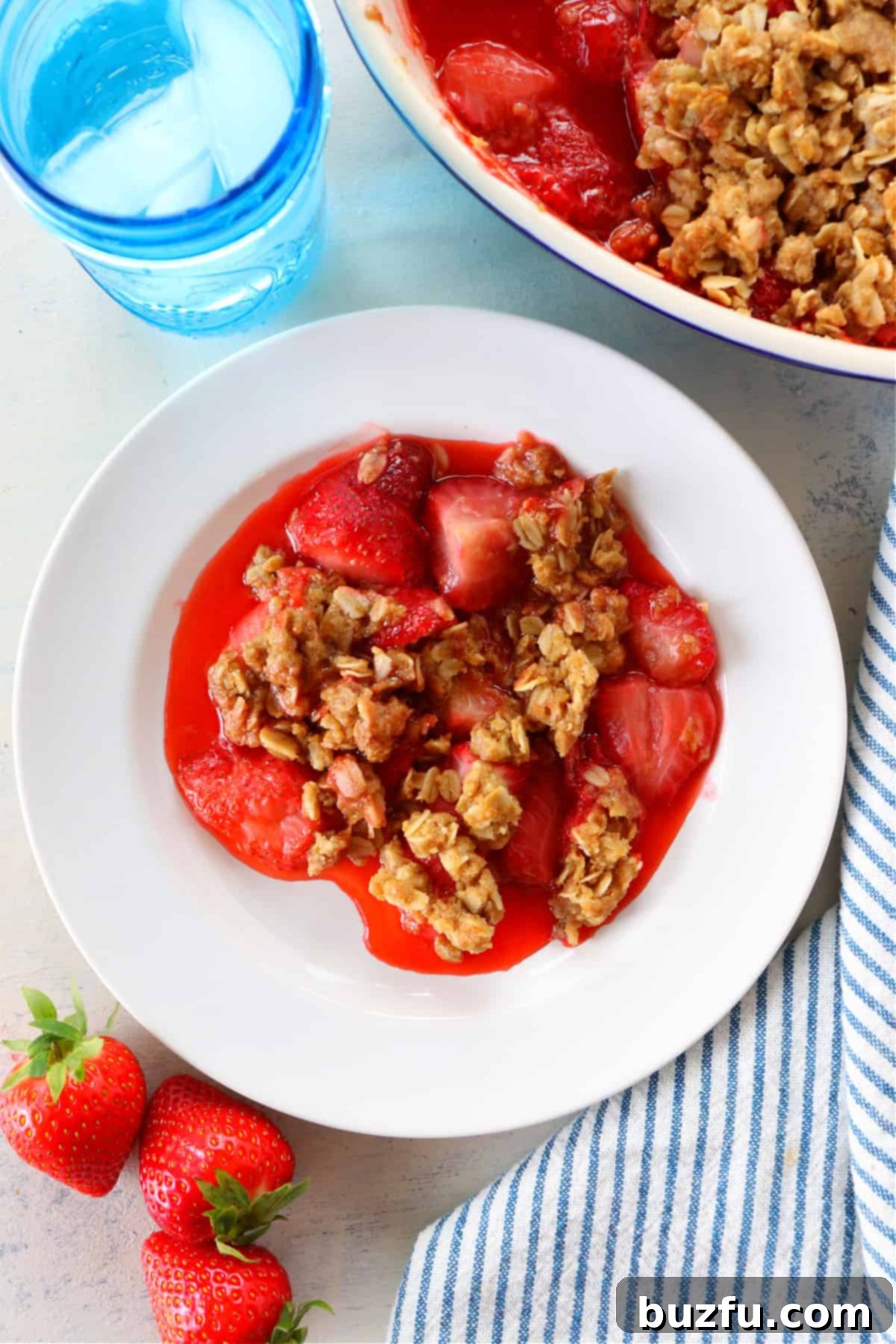 A generous serving of strawberry crumble on a white plate, ready to be enjoyed.