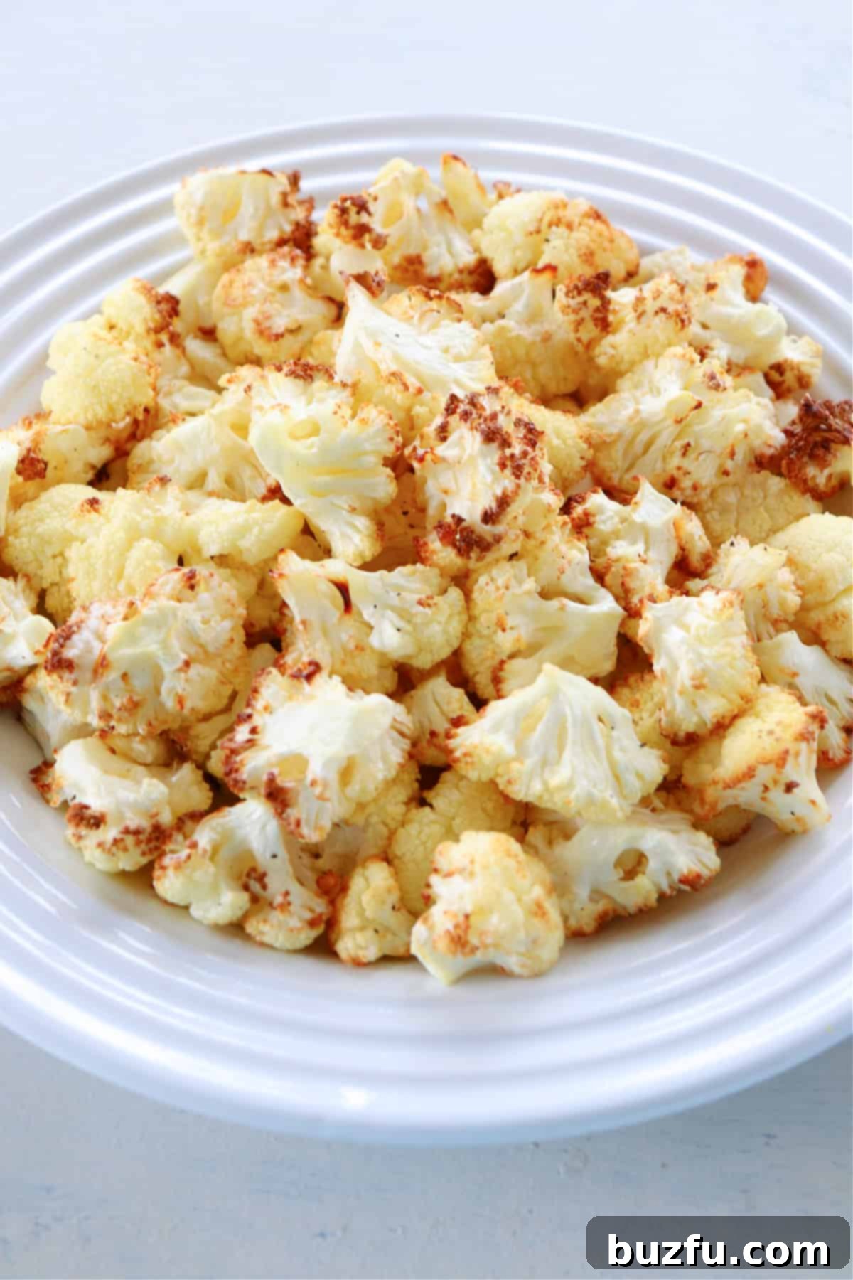 Perfectly air fried cauliflower florets served on a rustic plate, garnished with fresh herbs.