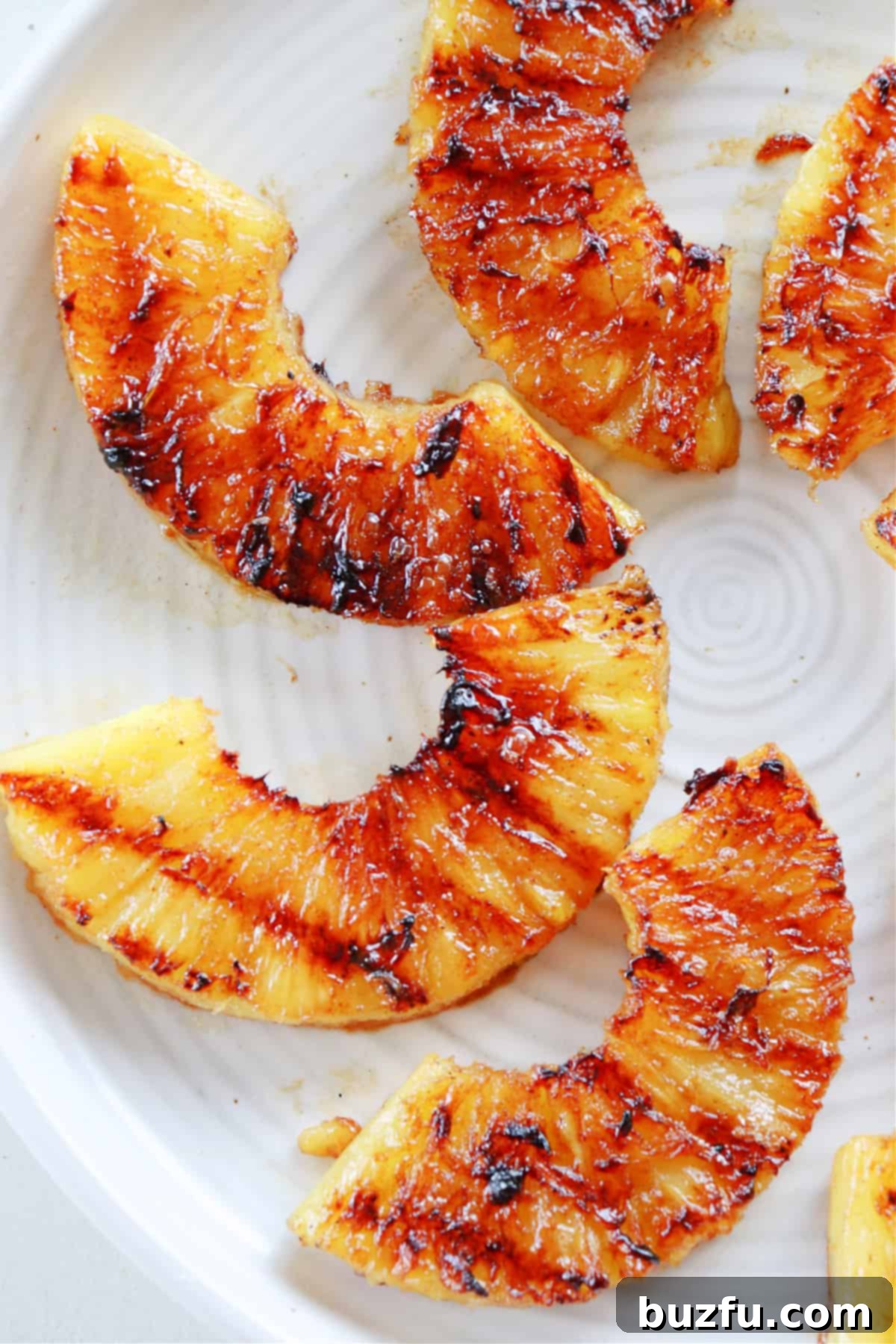 Perfectly grilled pineapple slices artfully arranged on a serving plate.