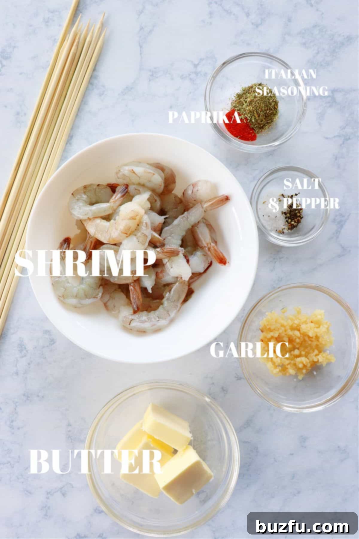 Fresh ingredients for grilled shrimp laid out on a marble board, including raw shrimp, butter, garlic, and seasoning.