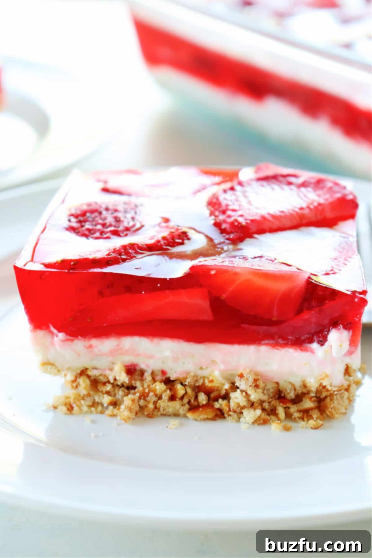 Strawberry Pretzel Salad recipe A perfectly portioned square of strawberry pretzel salad on a white plate, showcasing its distinct layers.