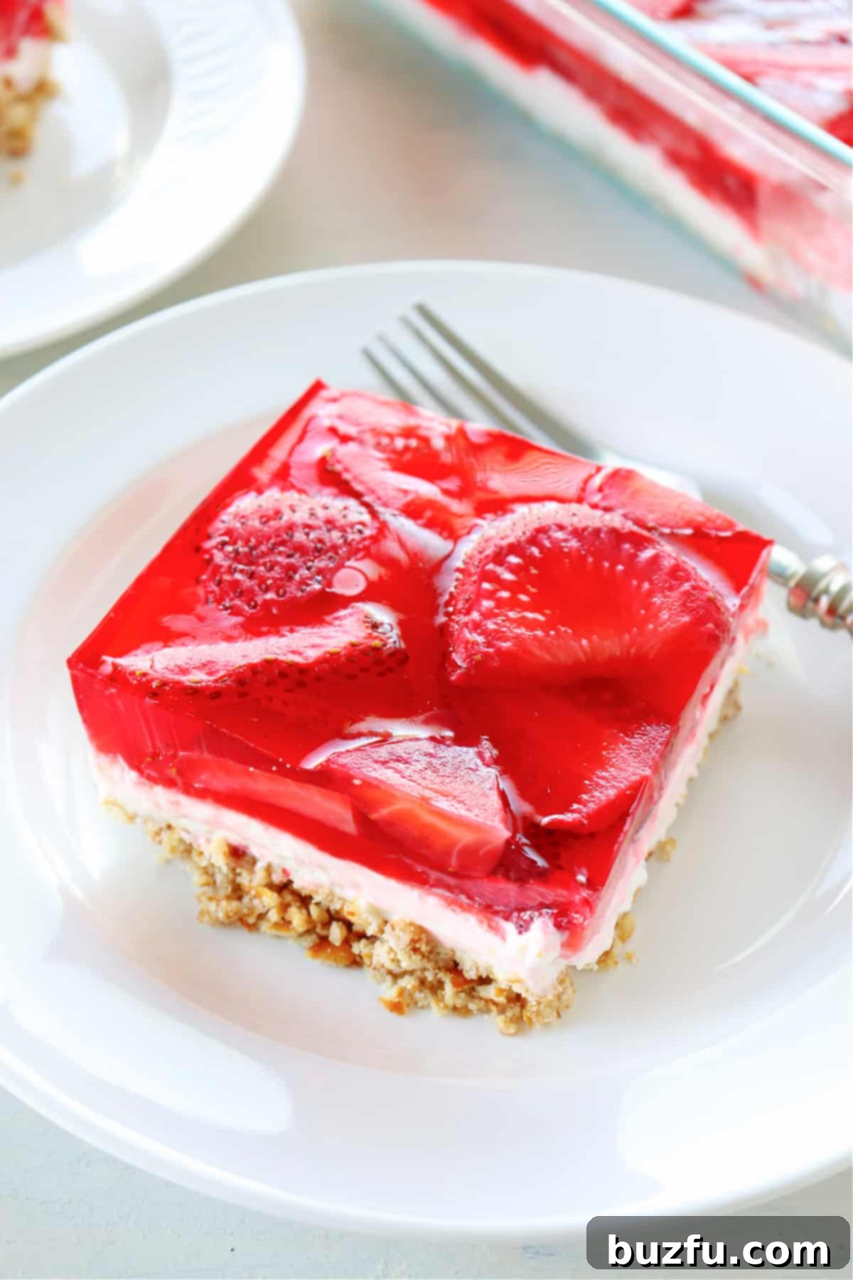 How to make strawberry pretzel salad. A perfectly portioned square of strawberry pretzel salad served on a small plate.