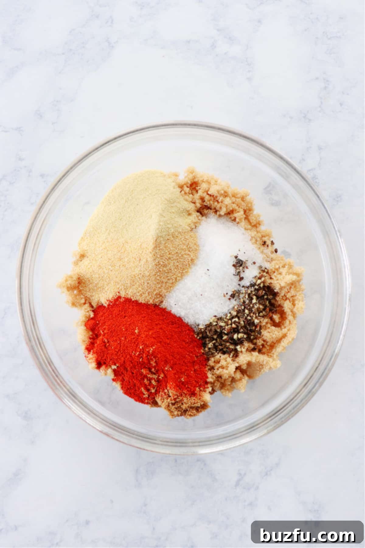 How to make dry rub from scratch All the dry rub spices combined in a large mixing bowl, being whisked together for a homogeneous blend.