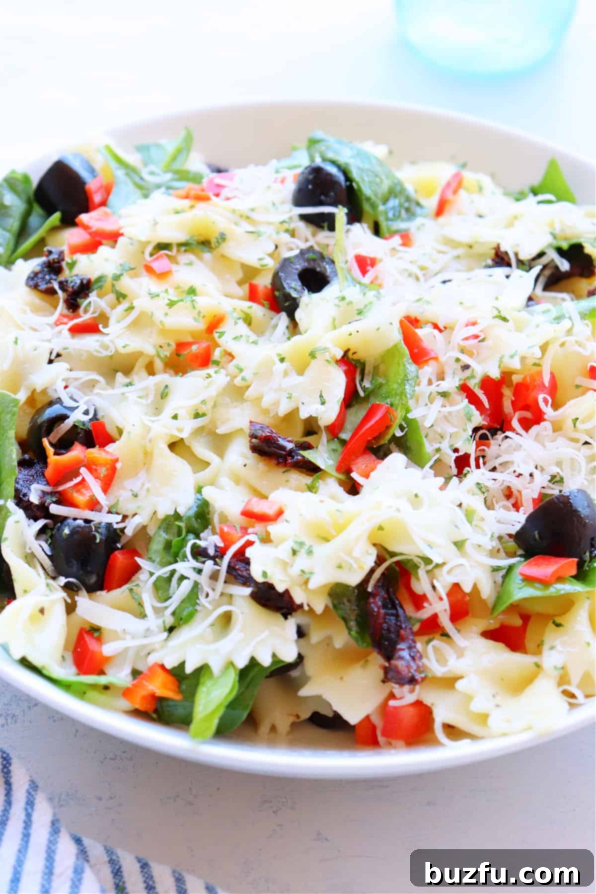 Simple Tuscan Pasta Salad Ready to Serve Close-up of Tuscan pasta salad with visible cheese, served in a rustic bowl.