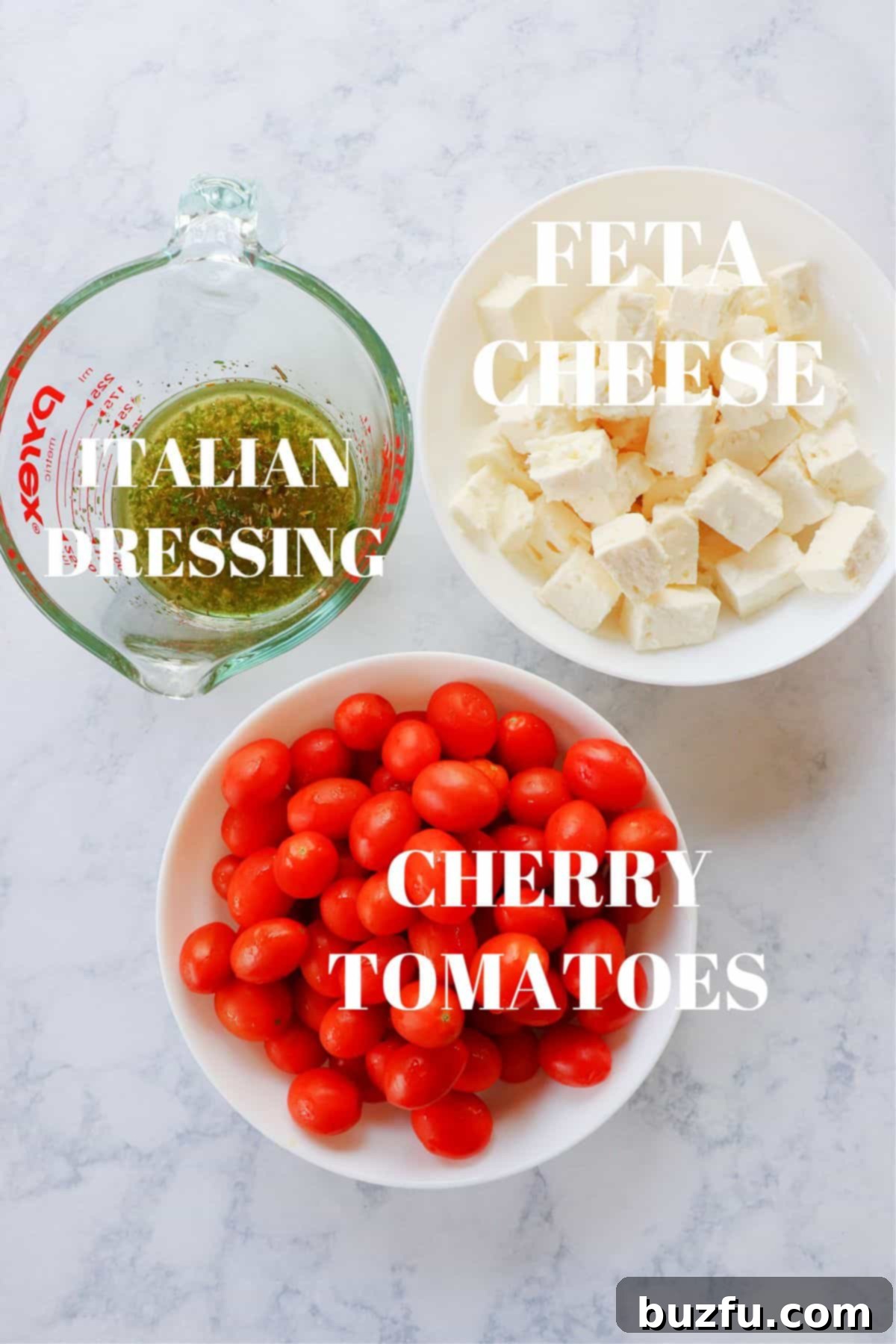 Tomato Feta Salad ingredients Fresh cherry tomatoes, a block of feta cheese, and a bottle of olive oil arranged on a marble board, ready for a delicious salad.