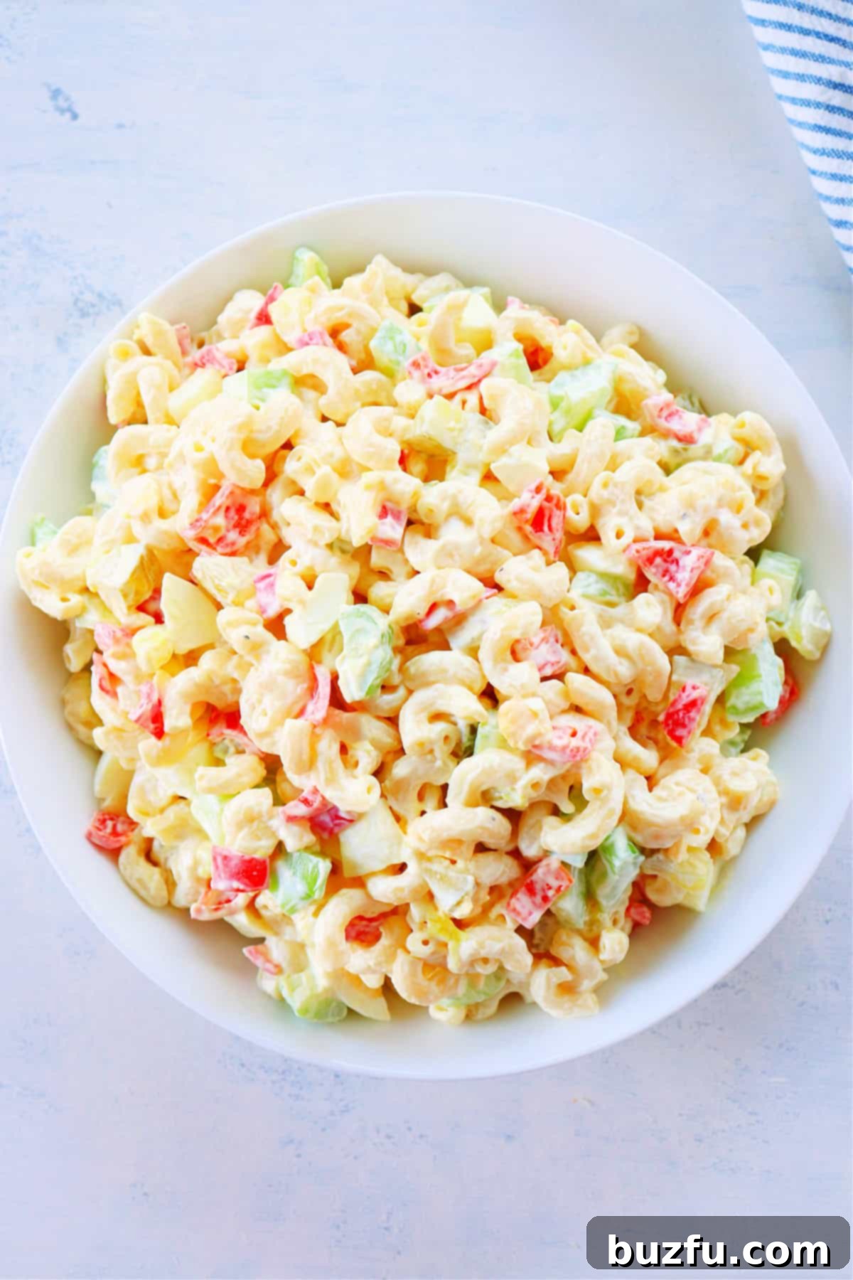 Delicious Macaroni Salad Close-up shot of a creamy macaroni salad in a white bowl, garnished with fresh herbs.